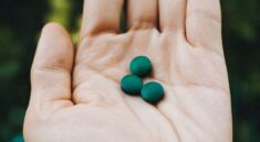 a hand holding two green pills in it's palm