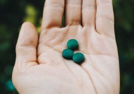 a hand holding two green pills in it's palm