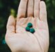 a hand holding two green pills in it's palm